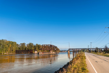 open movable railway bridge on the river between the asphalt road and the forest