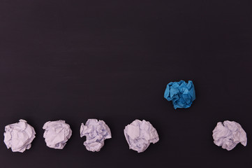 Crumpled white and blue paper on a black wooden background.