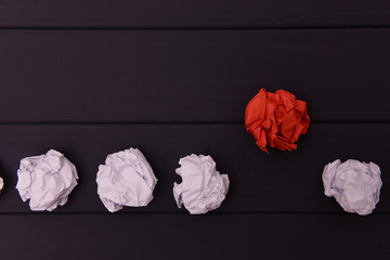 Crumpled white and red paper on a black wooden background.