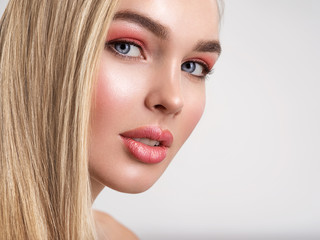 Portrait of a beautiful woman with a coral color makeup. Attractive blond  girl with  bright fashion make-up, posing at studio. Beautiful female face. Closeup portrait of pretty lady. Fashion model.