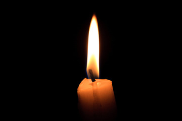 A single burning candle, isolated with black background, candle wick, closeup, macro. Hot fire flame in the dark night