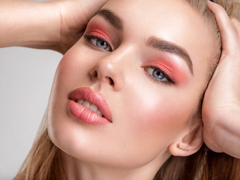 Portrait of a beautiful woman with a coral color makeup. Attractive blond  girl with  bright fashion make-up, posing at studio. Beautiful female face. Closeup portrait of pretty lady. Fashion model.