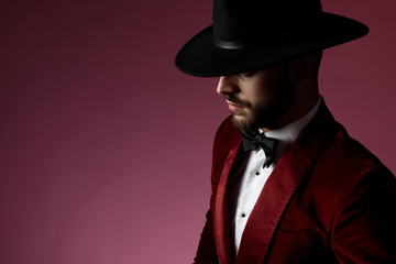mysterious young man wearing red velvet tuxedo and black hat