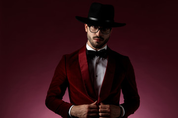 seductive fashion man wearing red velvet tuxedo and hat