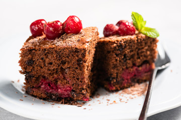 Cherry chocolate cake cut into squares on plate, closeup view. Isolated on white. Sweet chocolate dessert cake