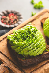 Avocado on rye bread toast garnished with chopped parsley, closeup view. Healthy snack, vegan or vegetarian breakfast