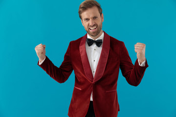happy elegant man in red velvet tuxedo celebrating victory