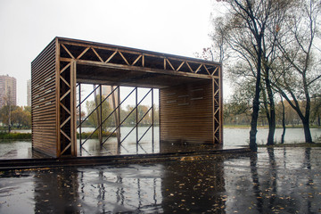 Wet wooden gazebo in the Park on a rainy autumn day overlooking the pond