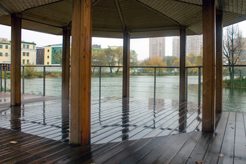 Wet wooden gazebo in the Park on a rainy autumn day overlooking the pond