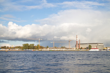 Tower cranes by the river in the city on a sunny day