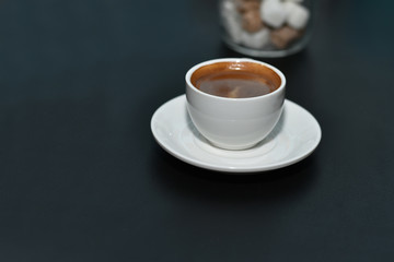 White cup of espresso coffee on a dark blurred background. Selective focus.