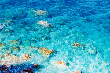 Naklejka na ściany i meble Blue emerald sea water with large stones beach. Rocky shore transparent turquoise bottom Malta