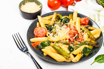 Vegan pasta penne with spinach, asparagus and tomato.