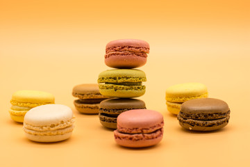 Obraz na płótnie Canvas delicious various macarons stacked and some spread around on warm colored background 