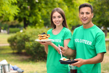 Young volunteers with food for poor people outdoors