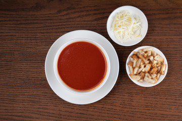 Traditional Turkish tomato soup with cheese and croutons aside isolated on wooden background