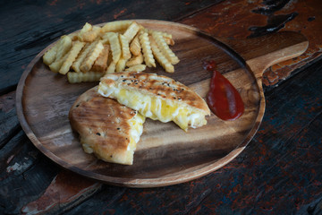 Grilled cheese panini sandwich served with fresh crispy french fries on rustic wooden kitchen table