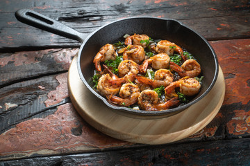 Top view of prawns shrimps roasted on pan with herbs isolated on rustic wooden kitchen table