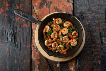 Top view of prawns shrimps roasted on pan with herbs isolated on rustic wooden kitchen table