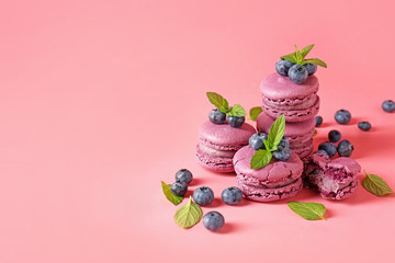 Tasty blueberry macarons with mint on color background