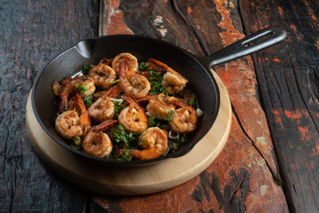 Top view of prawns shrimps roasted on pan with herbs isolated on rustic wooden kitchen table