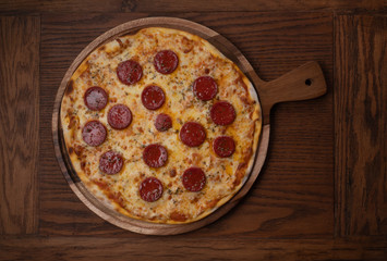 Top view of fresh tasty pizza with Turkish sausage and mozzarella cheese on wooden background