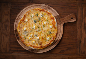 Top view of fresh tasty "Four cheeses" pizza on wooden background