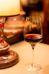 Calice di vino rosso vicino a una lampada da tavolo