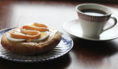 cup of coffee and sandwich with egg and caviar on wooden table