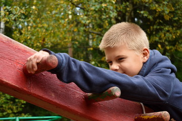 A boy climbs on wooden sports construction.