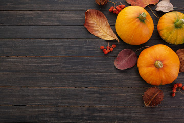 Pumpkins and fallen leaves on wooden background. Halloween, Thanksgiving day or seasonal background