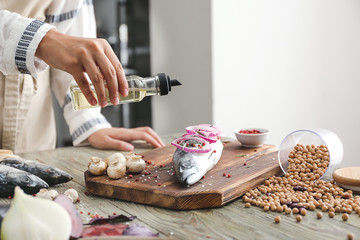 Woman preparing mackerel fish in kitchen, closeup