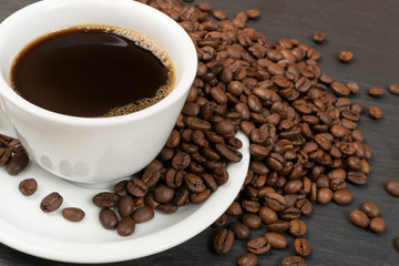Hot coffee cup and coffee beans on black background top view
