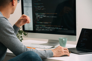 Programmer, working behind the desk, analysing code on the black screen.