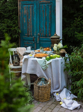 Beautifully decorated summer garden table with apple pies, tea cups, strawberry jam, old Russian samovar