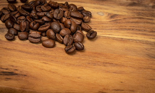 Dark brown whole coffee beans on wood background with copyspace