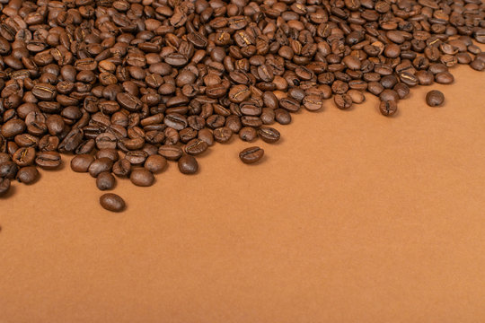 Dark brown whole coffee beans on wood background with copyspace