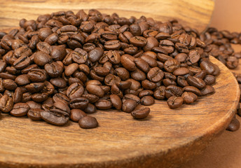 Dark brown whole coffee beans on wood background with copyspace
