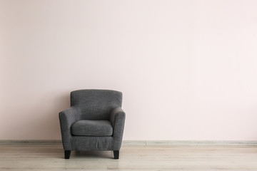 Comfortable armchair near light wall