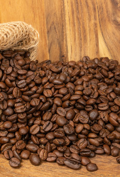 Dark brown whole coffee beans on wood background with copyspace