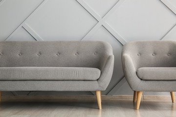 Modern sofa and armchair near light wall