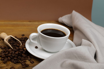 Hot coffee cup and coffee beans on wooden background