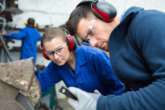 worker holding piece if metal by circular grinder