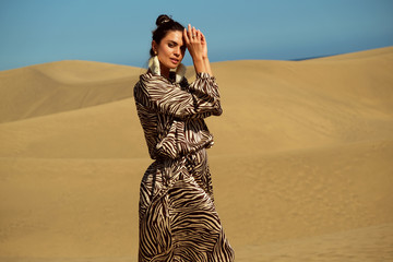 Fashion shoot of model wearing animal dress print on dessert.