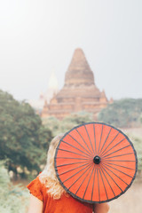 Woman with red umbrella overlooking pagoda and temple of ancient Bagan in Myanmar
