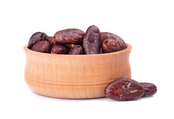 Peeled cocoa beans in the wooden bowl, isolated on white background. Roasted and aromatic cocoa beans, natural chocolate.