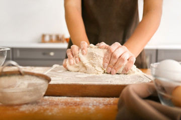 Woman kneading flour in kitchen