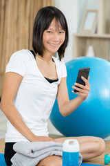 young woman relaxes with phone after yoga