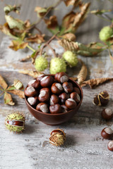 Chestnuts. A bowl of chestnuts. Leaves of a chestnut tree. Wood background. Selective focus.