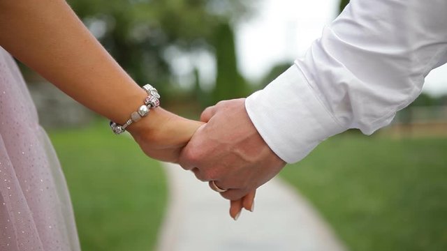 Man and woman hold hands. Groom gives hand to bride.